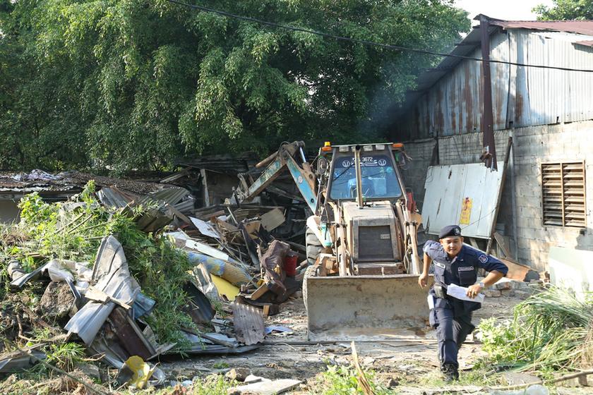 A Kuala Lumpur City Hall enforcement officer scurries out of the way as an excavator tears down one of the vacant houses in Kg Railway in Sentul. u00e2u20acu201d Picture by Saw Siow Feng