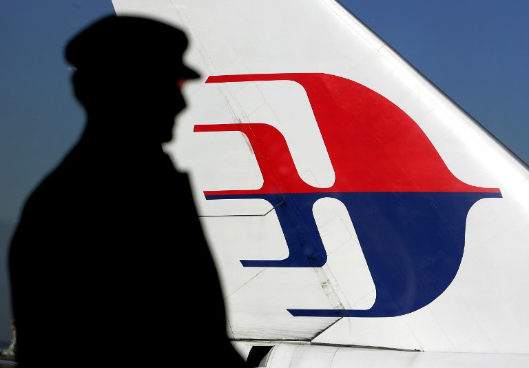 A file photo taken on July 5, 2005 shows a man silhouetted against a Malaysian Airlines plane tail as he looks out through a window at Sydney International Airport. u00e2u20acu201d AFP pic