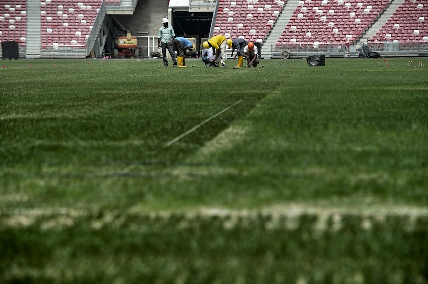 Labourers fixing the pitch of the new national stadium at sports hub complex in Singapore on May 21, 2014. u00e2u20acu201d AFP pic