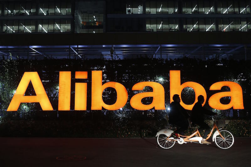 People ride a double bicycle past a logo of The Alibaba Group at the companyu00e2u20acu2122s headquarters on the outskirts of Hangzhou, Zhejiang province in this November 10, 2014 file photo. u00e2u20acu201d Reuters pic