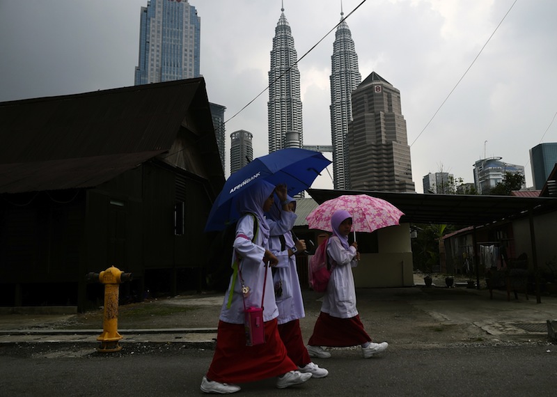 Malaysian schoolgirls take shelter under umbrellas as they return from school at the Kampung Baru neighbourhood of Kuala Lumpur on March 23, 2015. u00e2u20acu201du00c2u00a0AFP pic