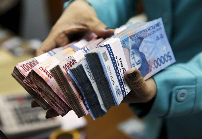 A woman holds Indonesian rupiah notes at money changer in Jakarta, March 26, 2015. u00e2u20acu2022 Reuters pic