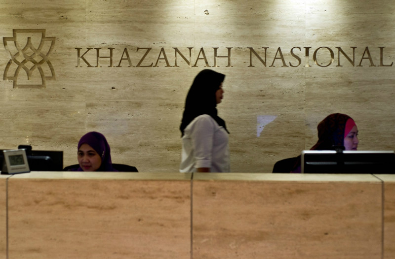 A woman walks past the Khazanah Nasional Berhad logo at the front desk of the Khazana Nasional office in Kuala Lumpur on August 29, 2014. — AFP pic