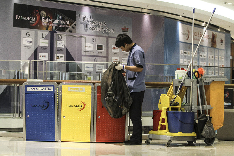 A cleaner sorts through waste at the recycling bins at Paradigm Mall in Petaling Jaya. u00e2u20acu201d Picture by Yusof Mat Isa