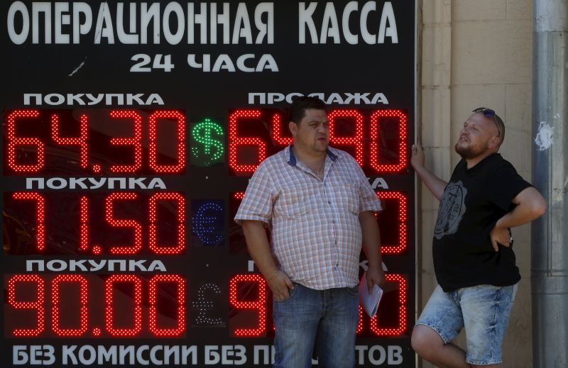 Men stand next to a board showing currency exchange rates of the US dollar, euro, and British pound (top-bottom) against the rouble in Moscow, Russia. u00e2u20acu201d Reuters pic