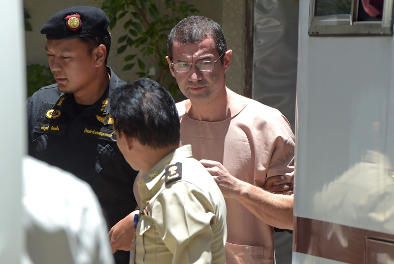 Swiss national Xavier Andre Justo (right), 49, is escorted by Thai officials as he leaves a courthouse in Bangkok on August 17, 2015. He was jailed for three years in Thailand for attempting to blackmail Saudi oil company PetroSaudi International. u00e2u20acu201d AFP