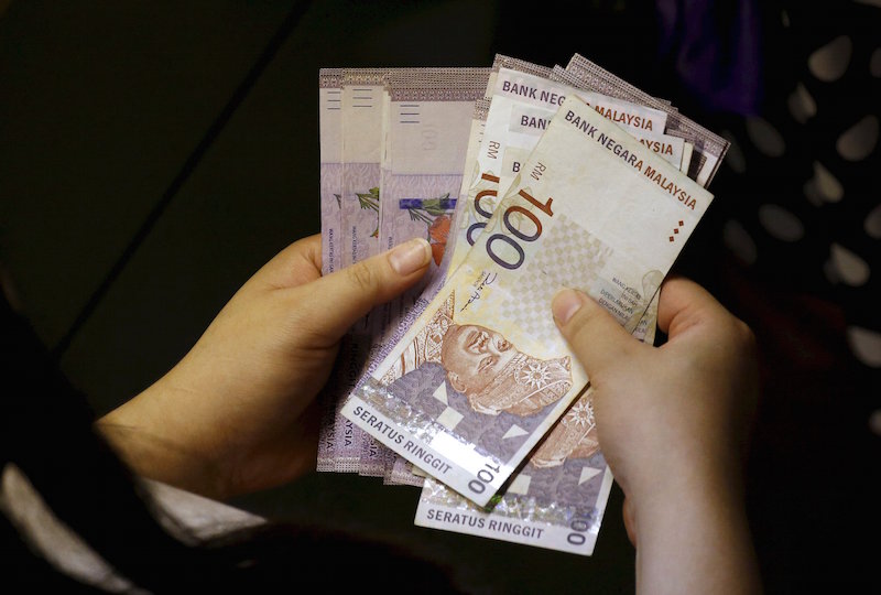 A customer counts her ringgit notes outside a money changer at the central business district in Singapore in this August 25, 2015 file photo. u00e2u20acu201d Reuters pic