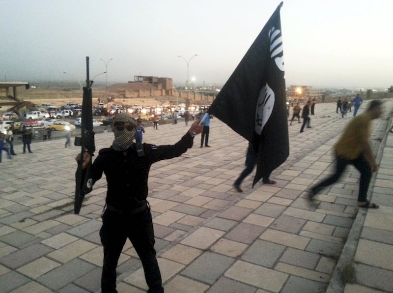 A fighter of the Islamic State of Iraq and the Levant (ISIL) holds an IS flag and a weapon on a street in the city of Mosul, Iraq, in this June 23, 2014 file photo. u00e2u20acu201d Reuters pic