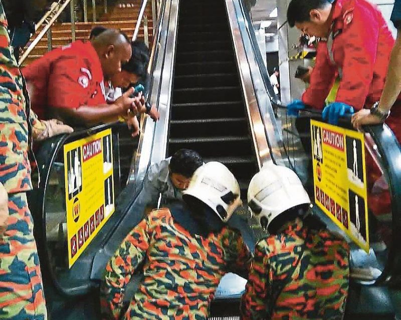 Firemen opening up the escalator to look for the forefoot of a three-year-old boy. u00e2u20acu2022 Malay Mail pic