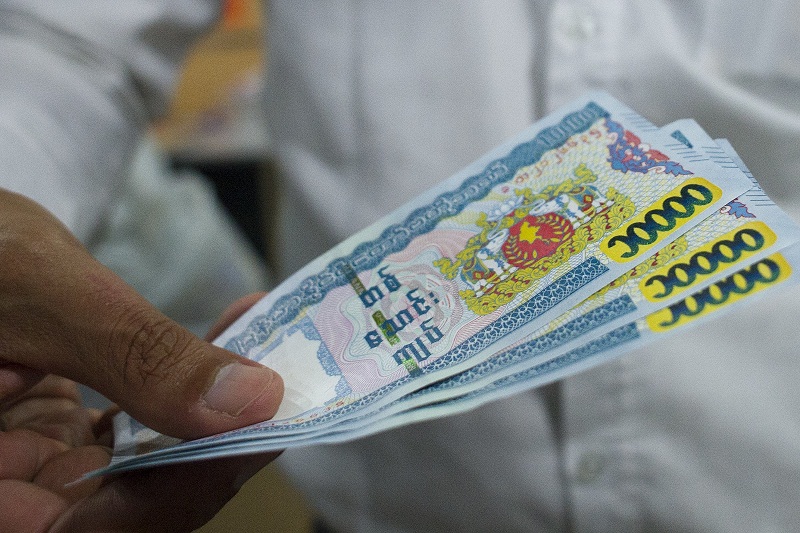An employee shows new ten thousand Myanmar Kyat notes at a bank in Yangon on July 1, 2015. u00e2u20acu201d AFP pic
