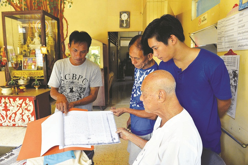 Boon Leau (left) shows his brothers Wintar (second left) and Charmarath and father Wan Dee a copy of the British agreement. u00e2u20acu201d Picture by R. Mahgeshan
