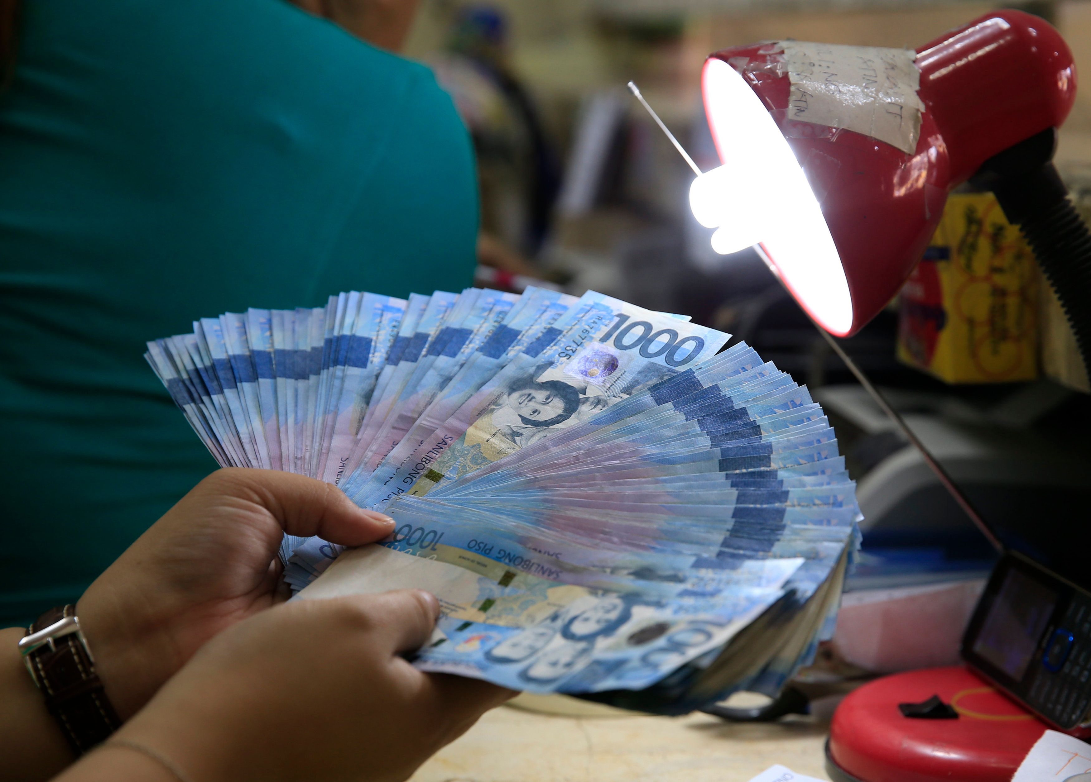 A worker inspects one thousand pesos bills inside a money changer in Manila, March 23, 2016. u00e2u20acu201d Reuters pic