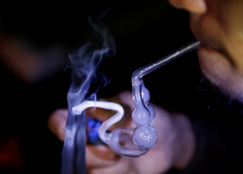 A drug addict uses a glass water pipe to smoke syabu, or methamphetamine, at an undisclosed drug den in Manila June 20, 2016. — Reuters pic