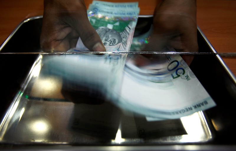 A money changer counts ringgit at a shop in Putrajaya, outside Kuala Lumpur, October 26, 2007. u00e2u20acu201d Reuters pic