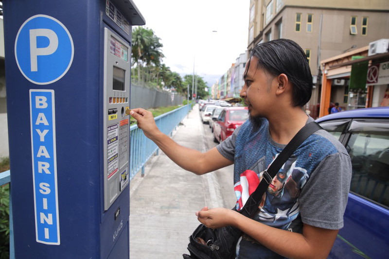 A motorist inserts money into an automated parking fees machine in Kuala Lumpur July 18, 2016. u00e2u20acu201d Picture by Choo Choy May