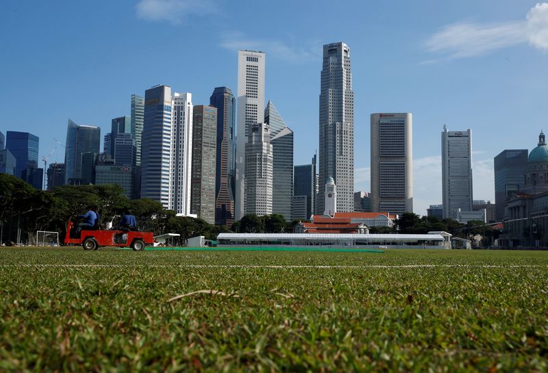 Workers tend to the pitch in the backdrop of the skyline of Singapore's central business district June 6, 2016. u00e2u20acu201d Reuters pic