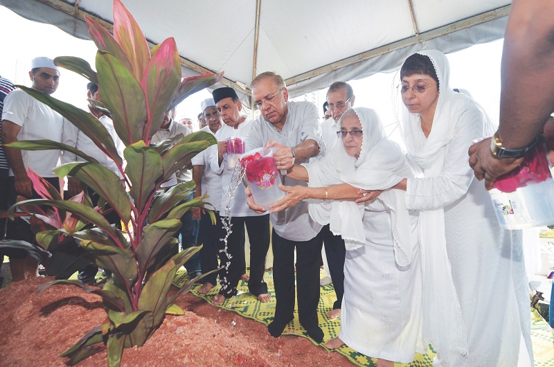 Rowshan (second right), assisted by Ameer (left) and daughter in-law Nadiya Pyar Ali, pours rose water on Mydin Mohamedu00e2u20acu2122s grave. u00e2u20acu201d Picture by Mukhriz Hazim