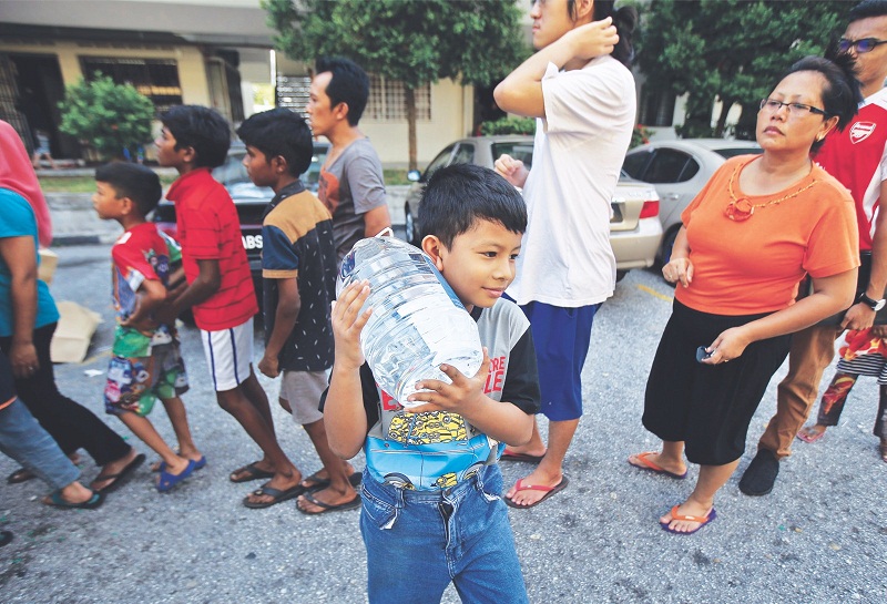 The smile says it all for this boy at Goodyear Court 2 in USJ 6 after receiving bottled water from Syabas.— Picture by Azneal Ishak