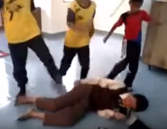 A screengrab of a video which went viral on YouTube show a group of primary school students kicking a schoolmate on the ground.