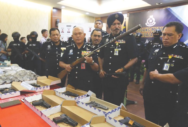 Datuk Seri Mohmad Salled holds the seized rifle. Second from right is city police chief Datuk Amar Singh. u00e2u20acu2022 Malay Mail pic