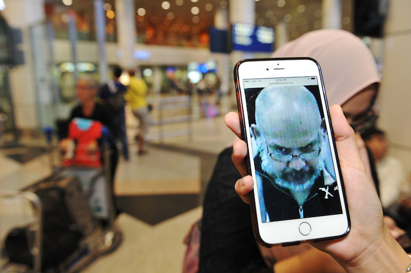 A journalist looks at a photo of convicted serial rapist Selva Kumar Subbiah on her phone at KLIA in Sepang February 7, 2017. u00e2u20acu201d Bernama pic