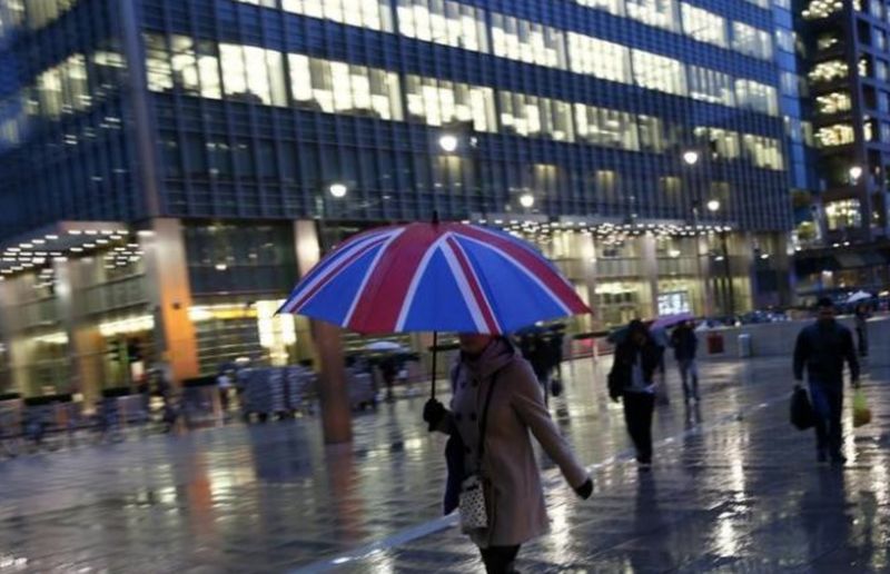 File picture shows workers walking in the rain at the Canary Wharf business district in London November 11, 2013. u00e2u20acu201d Reuters pic