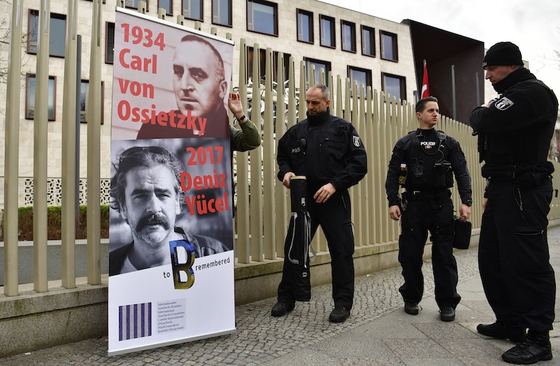 A man with a placard featuring detained German journalist Deniz Yucel in front of Turkish embassy is asked to leave by police, in Berlin on February 28, 2017. u00e2u20acu201d AFP pic