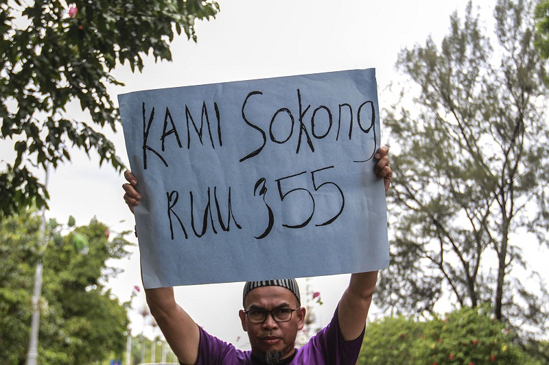 A man holds up a placard in support of the private memberu00e2u20acu2122s Bill by PAS president Datuk Seri Abdul Hadi Awang outside the Parliament building in Kuala Lumpur on April 6, 2017. u00e2u20acu201d Picture by Yusof Mat Isa