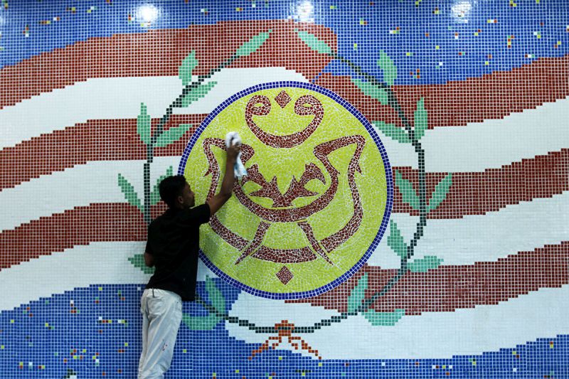 A man is pictured cleaning a section of the wall featuring the Umno logo at the Putra World Trade Centre, Kuala Lumpur on November 29, 2017. u00e2u20acu201d Picture by Miera Zulyana