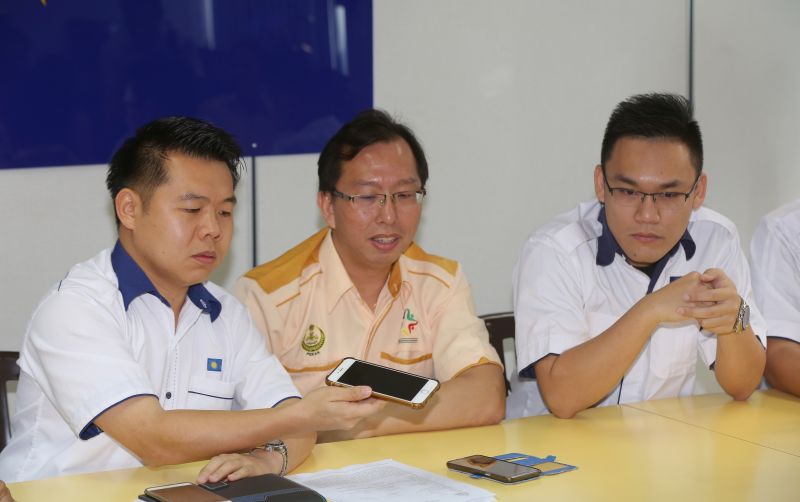 Ipoh Barat MCA Youth Chief Aldrich Low Guo Nan (left) together with Cheng Ming Tat, 35, (second left) listening to the recording of the call, where a scammer used death threat to extort money. u00e2u20acu2022 Picture by Marcus Pheong