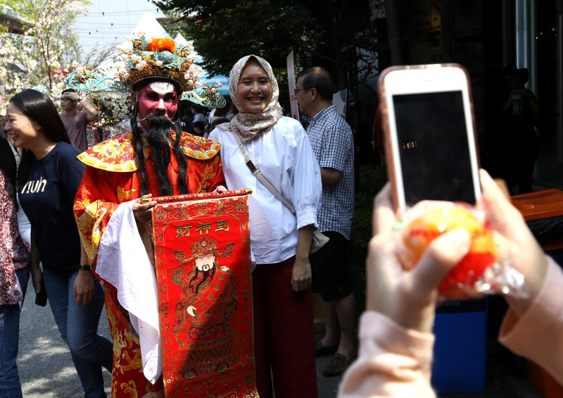 Maryam Khair, 26, poses for a picture with the God of Fortune who were handing out free Mandarin oranges at Gong Xi RIUH in Bangsar February 11, 2018. u00e2u20acu201d Picture by Zuraneeza Zulkifli