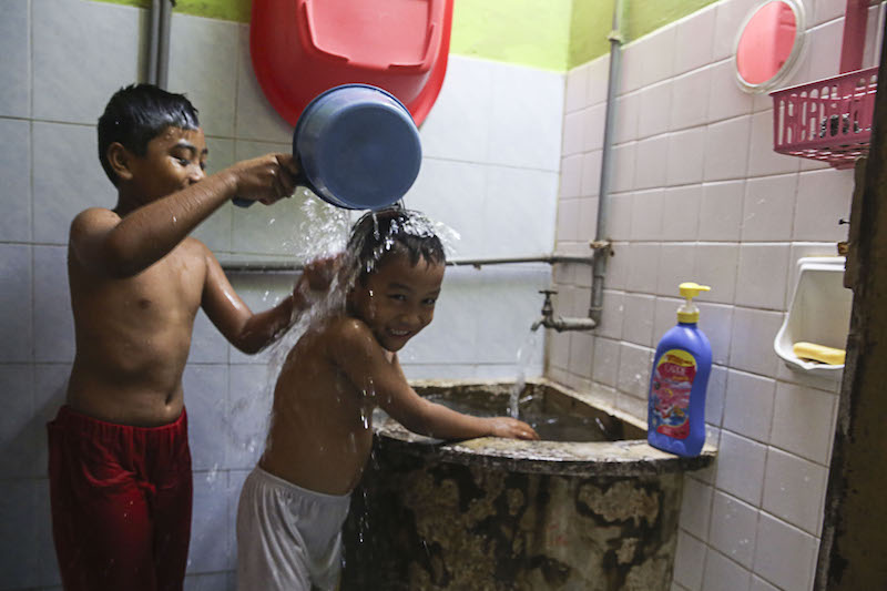 Brothers Mohd Aiman Suhendy (right) and Mohd Haikal Suhendy take a shower after water supply was restored to the Hulu Klang area, March 10, 2018.u00c2u00a0u00e2u20acu201d Picture by Yusof Mat Isa