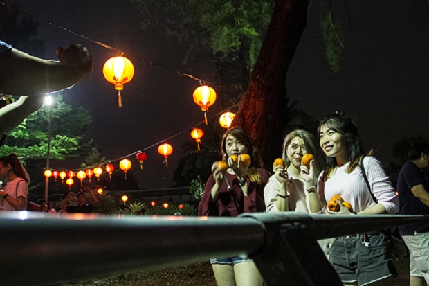 Accounting student Chin (left) and communications student Rebecca Ng (right) prepare to toss mandarin oranges into the Taman Jaya lake during MBPJ's Chap Goh Meh celebration in Petaling Jaya March 2, 2018. u00e2u20acu201d Pictures by Shafwan Zaidon