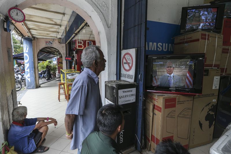 People watch a ‘live’ television broadcast of Prime Minister Datuk Seri Najib Razak as he announces the dissolution of Parliament in Kuala Lumpur April 6, 2018. — Picture by Azneal Ishak