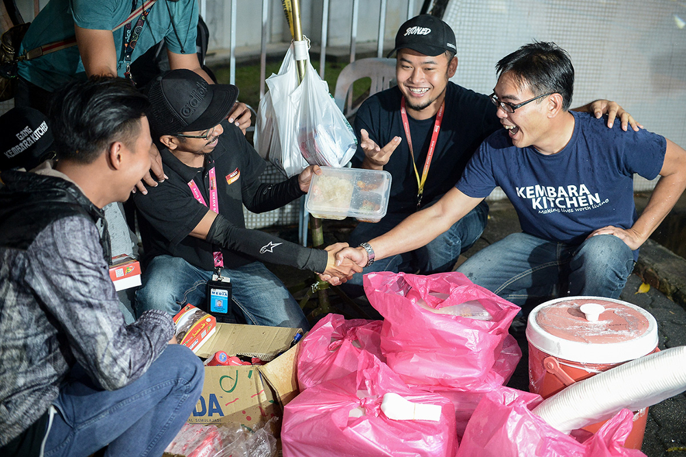 Kembara Kitchen founder William Cheah (right) hands out food as a gesture of gratitude to the press and policemen standby at Datuk Seri Najib Razaku00e2u20acu2122s house in Taman Duta, May 19, 2018. u00e2u20acu201d Picture by Mukhriz Hazim