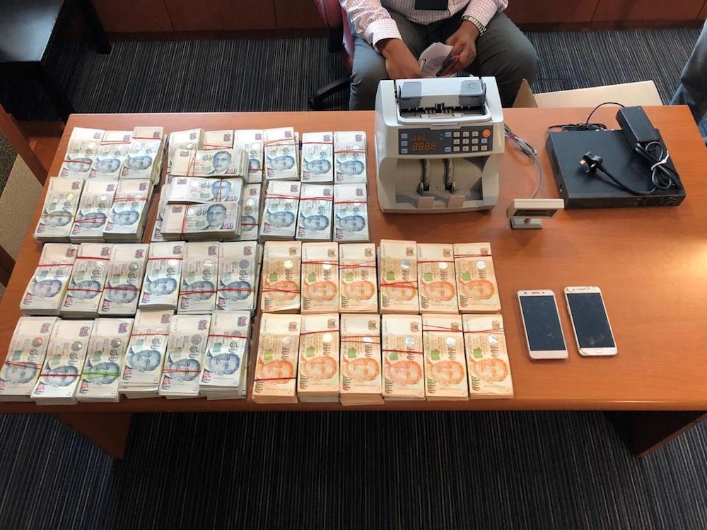 The seized items from the two men were shown during the press conference, and they included stacks of money in S$50 and S$100 denominations, a banknote counter, a hard disk consisting of CCTV footage belonging to the accused, and two mobile phones. — TODAY pic