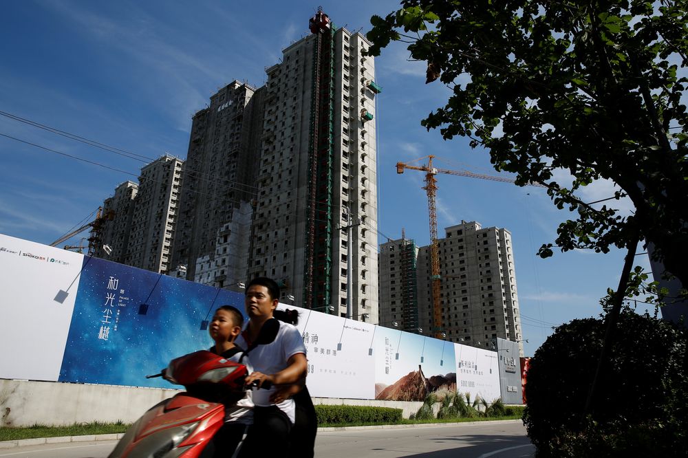 A man and a boy ride an electric scooter past the shells of apartment blocks outside a construction site in Beijing, China, August 16, 2018. u00e2u20acu201d Reuters pic