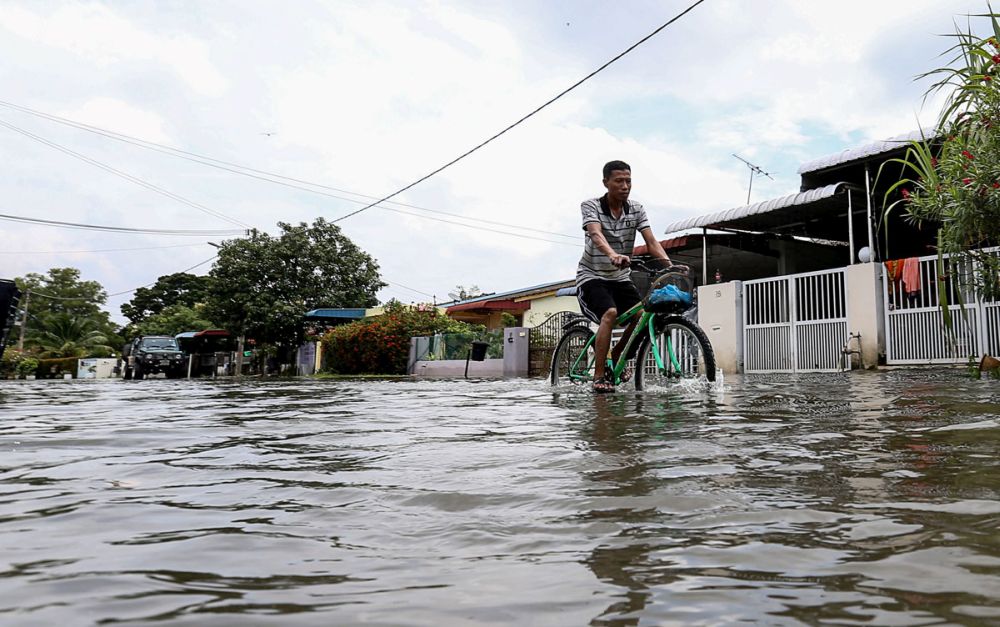 A man cycles past flooded streets of Taman Tembikai following heavy rain in Penang October 4, 2018. u00e2u20acu2022 Picture by Sayuti Zainudin