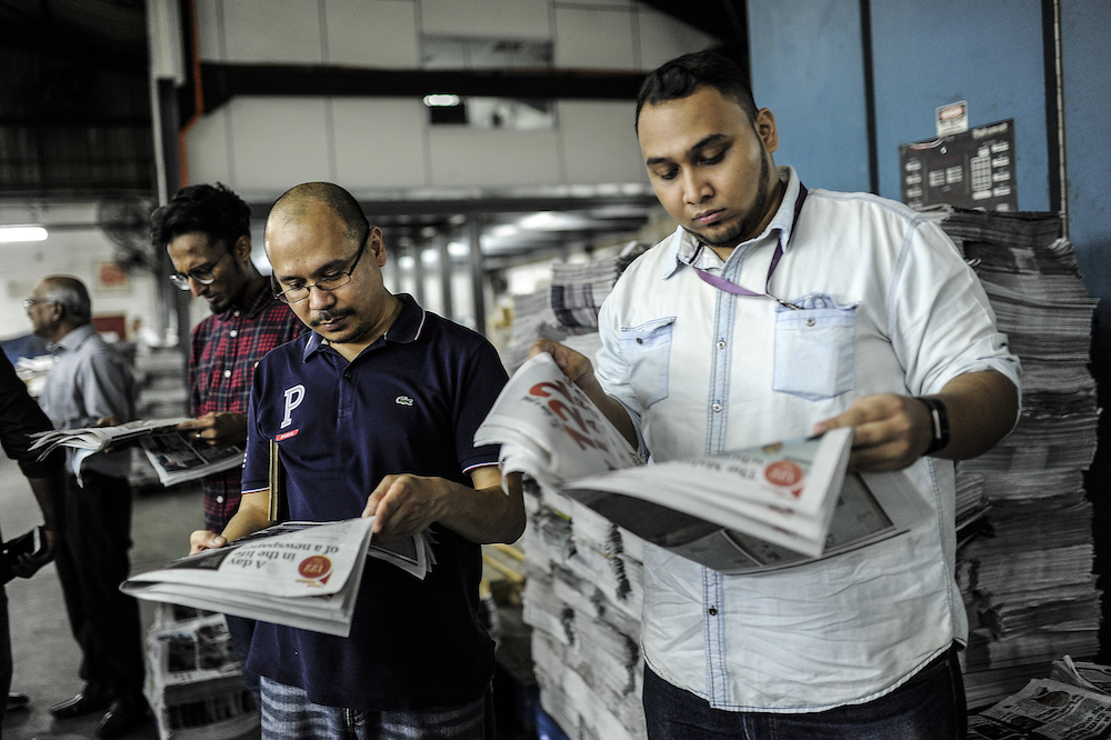 Malay Mail staff read the newspaper’s final edition in Petaling Jaya November 30, 2018. — Picture by Shafwan Zaidon