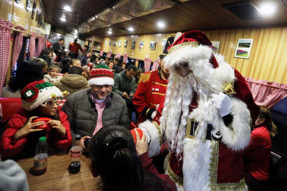 A man dressed as Santa Claus distributes gifts on board the tourist train 'La Sabana' decorated with Christmas lights in Bogota, Colombia December 11, 2018. u00e2u20acu201d Reuters pic 