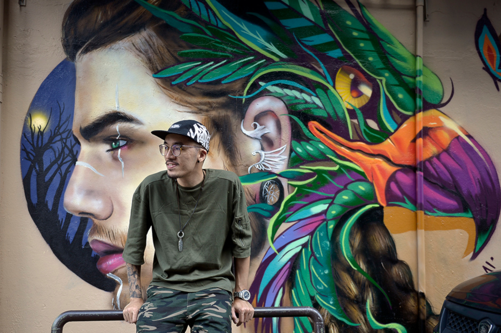 Graffiti artist Kenji Chai against his recent artwork along Jalan Telawi in Bangsar, Kuala Lumpur. u00e2u20acu201d Picture by Mukhriz Hazim
