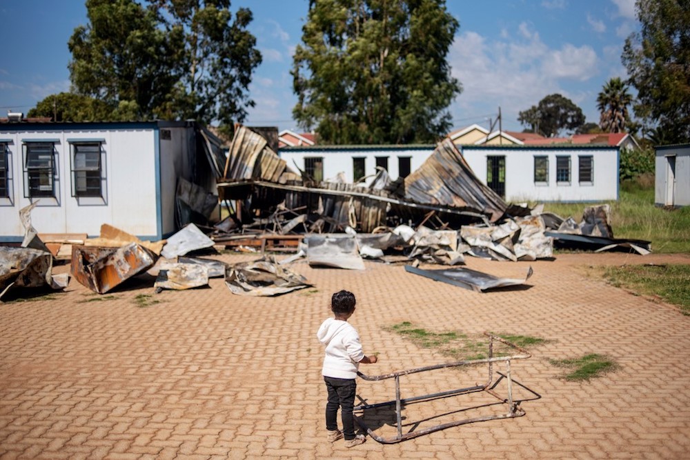 A young child belonging to the coloured community of Eldorado Park stands in the courtyard of the Oakdale Secondary School April 18, 2019, where several classrooms were destroyed during a student strike. — AFP pic