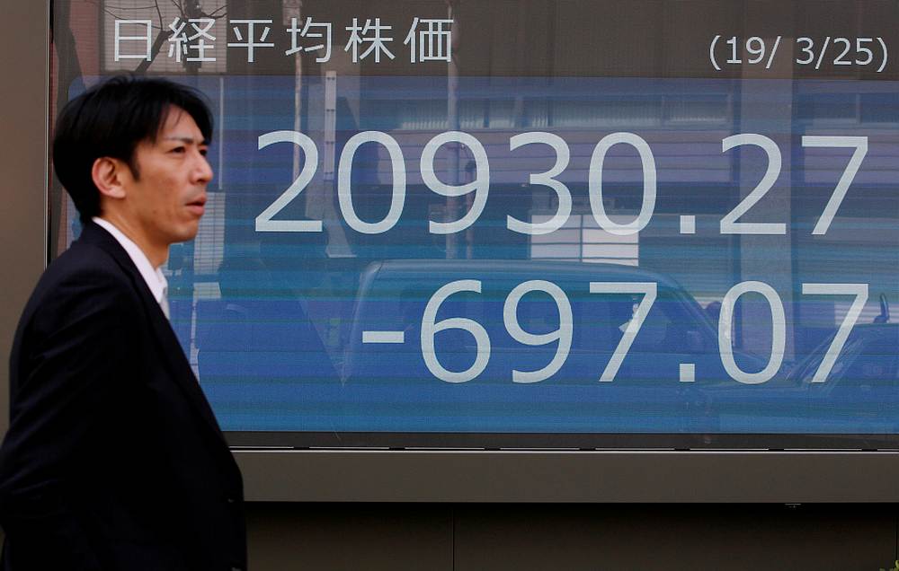 A man walks past an electronic board showing the Nikkei stock index outside a brokerage in Tokyo March 25, 2019. u00e2u20acu201d Reuters pic