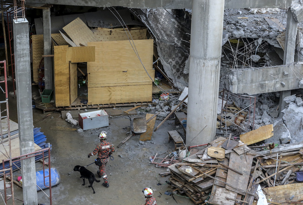 Fire and rescue personnel enter the site of the Gombak Integrated Transport Terminal car park collapse with tracking dogs in Kuala Lumpur May 23, 2019. u00e2u20acu201d Picture by Firdaus Latif