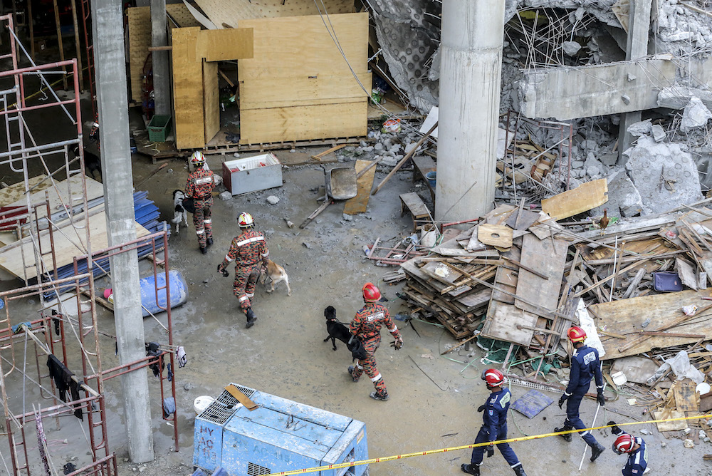 Fire and rescue personnel enter the site of the Gombak Integrated Transport Terminal car park collapse with tracking dogs in Kuala Lumpur May 23, 2019. — Picture by Firdaus Latif