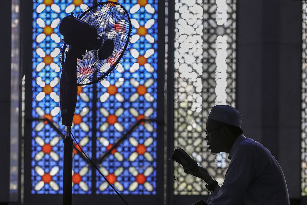 The silhouette of a man as he reads the Quran during the holy month of Ramadan at the Sultan Salahuddin Abdul Aziz Shah Mosque in Shah Alam, May 18, 2019. u00e2u20acu201d Yusof Mat Isa