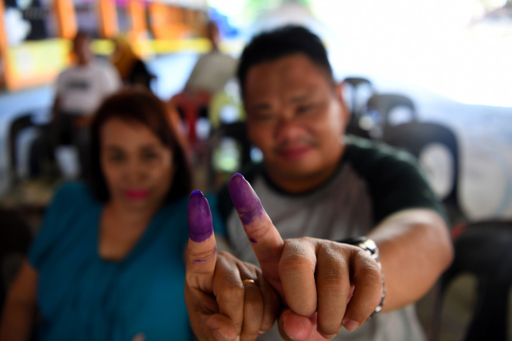 Tan Hat Tiong, 50, and his wife Ainawait Saari, 66, show their fingers after casting their votes in the Sandakan by-election at Sekolah Kebangsaan Tanjung Papat 1 and 2 on May 11, 2019. — Bernama pic