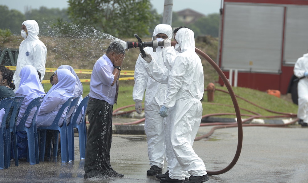 Fire and Rescue Department personnel douse a student with water at Sekolah Menengah Kebangsaan (SMK) Tanjung Puteri Resort in Pasir Gudang June 24, 2019. u00e2u20acu201d Bernama pic