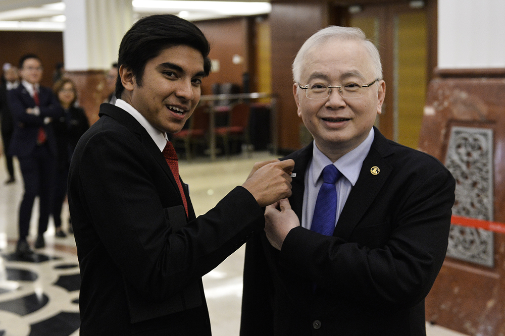 Minister of Youth and Sports Syed Saddiq Abdul Rahman pinned on a support for the Undi 18 Bill button on Ayer Hitam MP Datuk Seri Wee Ka Siong  at Parliament on July 16, 2019. — Picture by Miera Zulyana