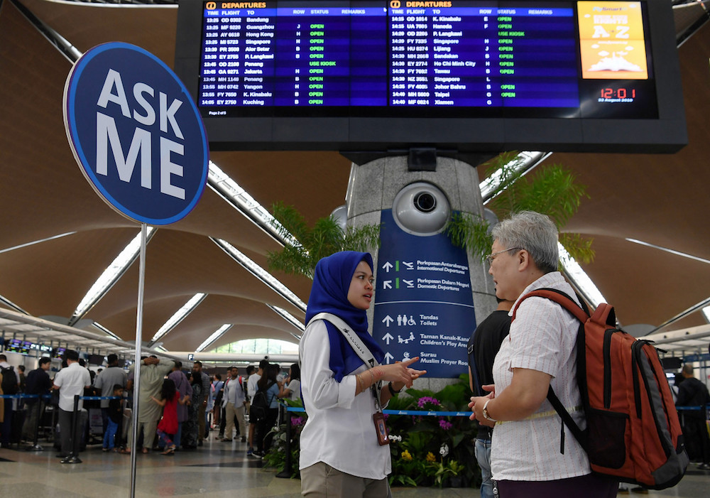 A MAHB Airport CARE Ambassador assists a passenger at KLIA in Sepang August 22, 2019, during a systems outage. u00e2u20acu201d Bernama pic